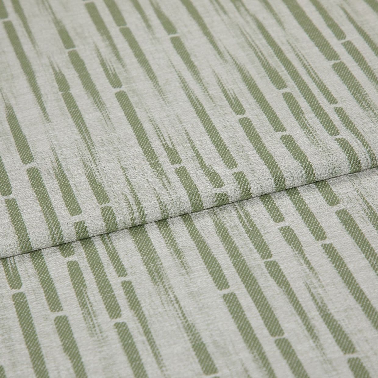 Textured upholstery fabric with vertical olive-green dashed stripes, folded once across the center creating an overlapping seam; close-up view with soft, even lighting and neutral, fabric-only background.