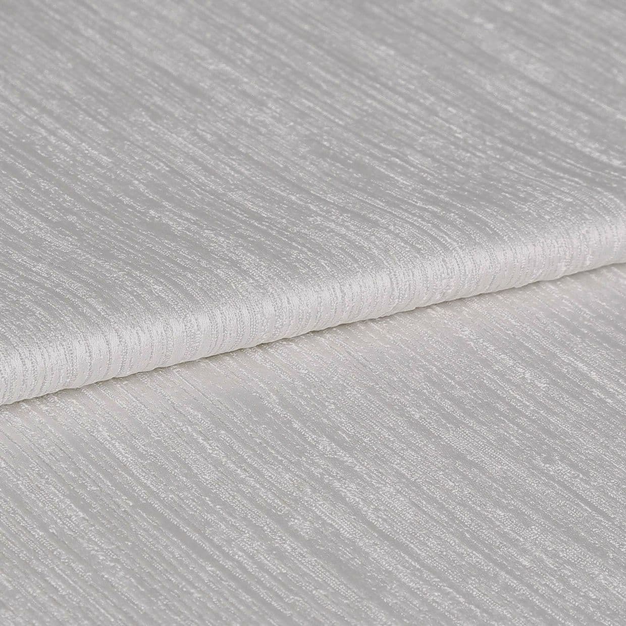 Textured ivory curtain fabric, folded over itself showing horizontal ribbed sheen; close-up view on a neutral surface with soft, diffuse lighting highlighting the weave.