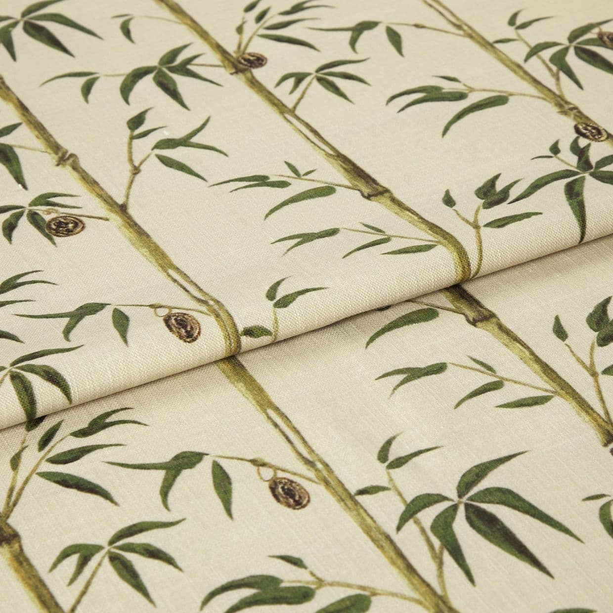Folded fabric sample in cream background with linear print of bamboo shoots and leaves.