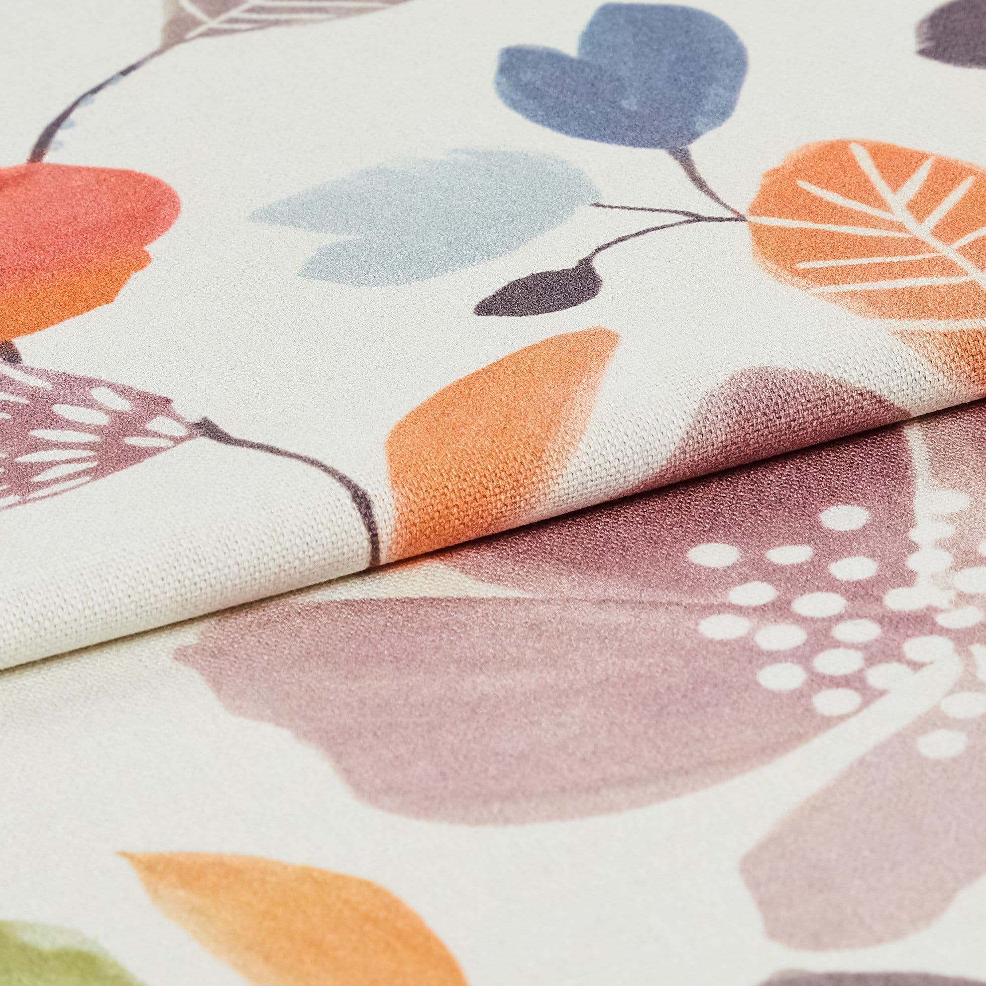 Folded floral-printed textile, two layered panels with pastel orange, blue and purple leaf motifs; folded edge overlaps the lower layer. Close-up, studio-lit view highlighting woven texture and soft, neutral lighting.