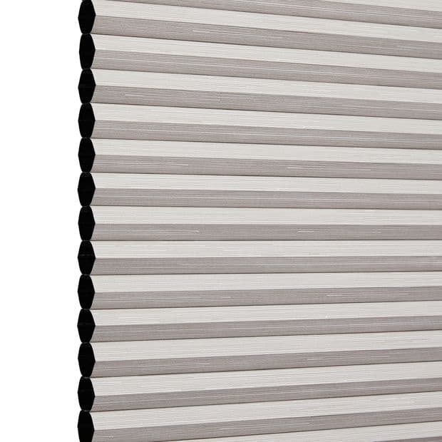 Honeycomb cellular blind, lowered and fully closed with visible hexagonal cell ends and beige horizontal pleats, blocking light; photographed against a plain white studio background.